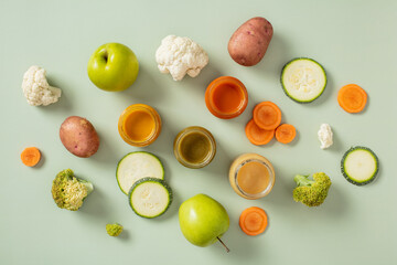 Fresh fruits, vegetables, and colorful purees in glass jars on light green background