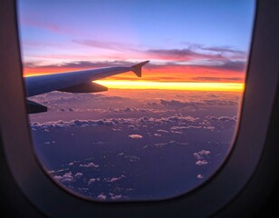 Airplane window view of sunset over clouds