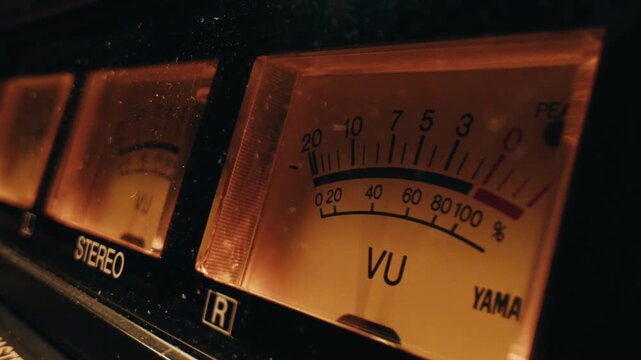 Analog dial indicator of audio signal level amplifier. Vintage arrow moves with sound level. Round classic volume indicator with yellow backlight, VU meters. Close-up of old measuring dB decibels