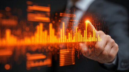 Businessman interacting with futuristic digital orange bar graphs and data charts displaying financial analytics and market trends in technology concept