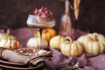 A charming autumn dining setting featuring white pumpkins, a folded linen napkin with dried florals, and a vintage glass, ideal for Thanksgiving dinner and seasonal table decor