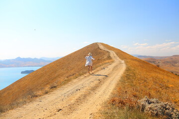 a girl running up a mountain on rocks near the sea in the wind