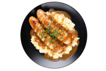 Delicious bangers and mash with gravy and herbs on black plate