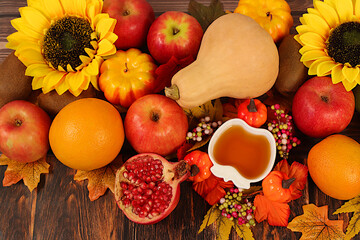 Thanksgiving banner, autumn background with apples, pomegranates, pumpkins, honey, grapes, flowers under sunflowers and leaves on wooden table, harvest concept, healthy natural food advertising