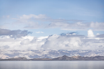 Panorama landscape of Lake Karakul in the Pamir mountains in the Tien Shan against the background of high snowy rocky peaks with clouds, morning panorama of the lake for the background