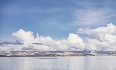 Fototapeta premium Panorama landscape of Lake Karakul in the Pamir mountains in the Tien Shan against the background of high snowy rocky peaks with clouds, morning panorama of the lake for the background