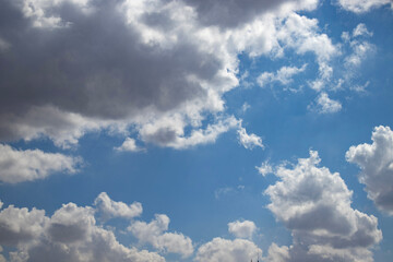Wide view of blue sky with bright cumulus and dark storm cloud. Natural weather background for banner, poster, wallpaper, climate concept, meteorology theme, travel mood, copy space, web and print.