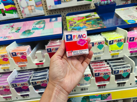 Potsdam, Germany - September 04, 2025: Hand holding FIMO Soft modeling clay package in a colorful art supply store, showcasing vibrant colors and creative possibilities for artists and crafters
