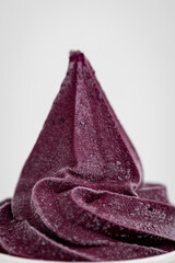 Close-up of dark berry frozen yogurt swirl in minimal white cup on light background
