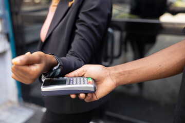 Customer uses her mobile application to pay a courier delivering meal package. The contactless payment method emphasizes modern food service and efficient takeaway job practices.