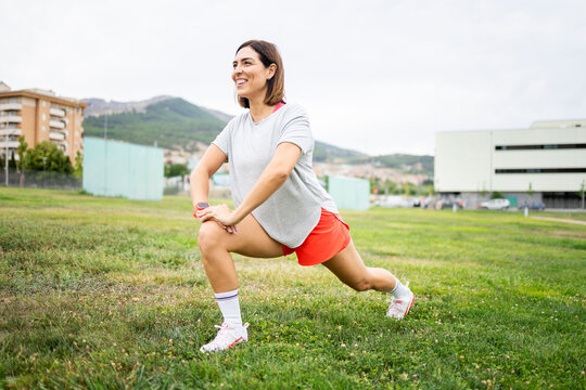 An attractive woman between 30 and 40 years old is doing sports outdoors.The woman is stretching her legs forward.Concept of adult women doing sports.