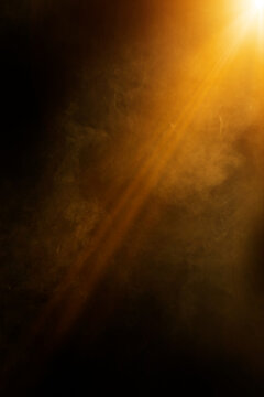 Golden light beam illuminating swirling smoke or fog on a black background, creating a dramatic and mysterious atmosphere