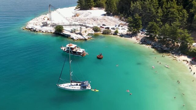 Yachts in sea on Porto Vathy beach, Thassos Island, Greece. Amazing beach with clear blue water. Aerial panoramic drone view from above, top view from drone. Summer holidays Europe
