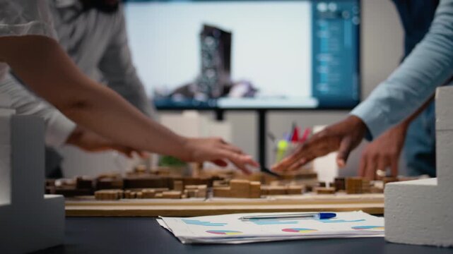 Close up of developers work together on layout city planning initiative with residential project for infrastructure growth, experts using 3D models for site preparation. Master plan. Camera A.