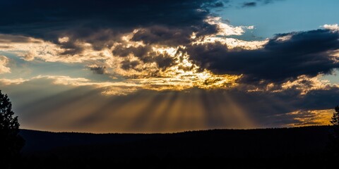 A breathtaking sunset paints the sky with golden rays breaking through dramatic storm clouds.