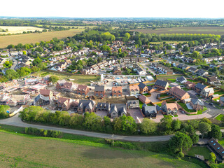 Aerial view of near completed family and first time buyer homes at the edge of a rural village in Essex, UK. The older village is in the background.