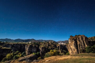 Nighttime view of a valley with a starry sky