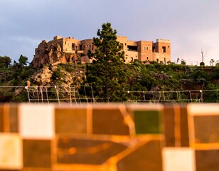 Ancient-looking building atop a hillside, framed by a tiled wall