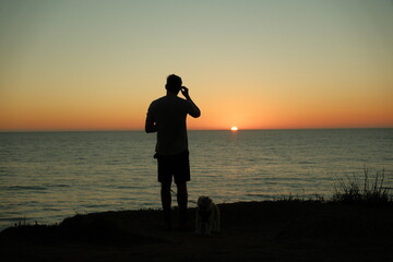 Shadow silhouette of man watching the majestic orange sunset at Sunset Cliffs, Ocean Beach, San Diego, California © Sarah