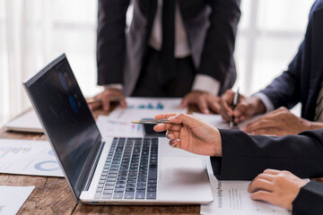 Business team analyzing data on laptop and documents in meeting room