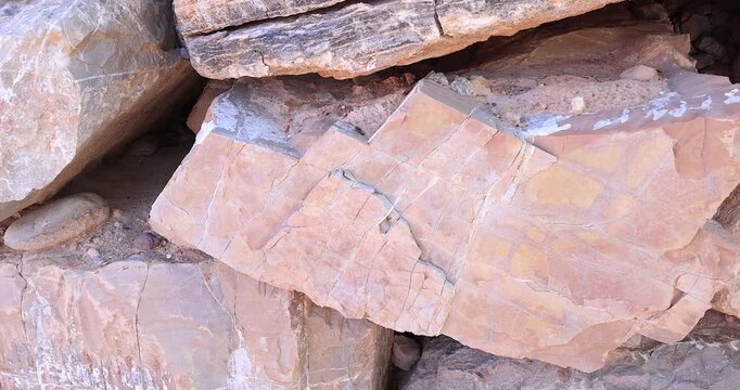 Closeup of broken by erosion tan color rock in dry stack of chipped and damaged stones 4k