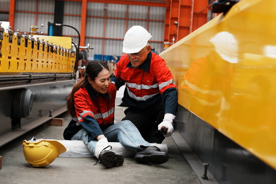 Asian woman, a product inspection worker, had an accident and fell, hurting her ankle, and sat on the factory floor. A senior supervisor came to help.