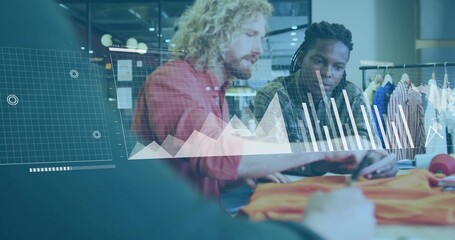 Two male colleagues reviewing orange garment in studio, with garment rack and digital data overlay