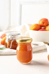 Jar with sweet apricot jam on white background