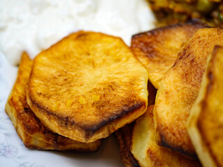A close up photograph of golden brown crispy fried potato slices served as a delicious side dish or appetizer with a perfectly cooked and textured surface