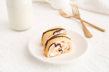 Plate with pieces of sweet sponge cake roll on white background