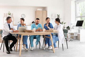 Doctors with medical interns having lunch at table in kitchen