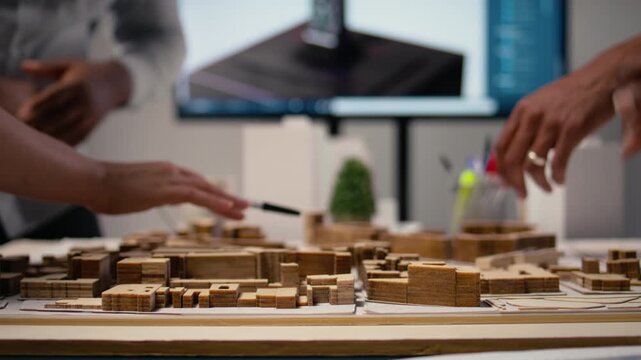 Close up of diverse developers focuses on 3D models layout presentations with detailed city planning for a residential area, waiting for project approval. Infrastructure growth master plan. Camera A.