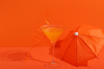 Cocktail with straw and umbrella on orange table