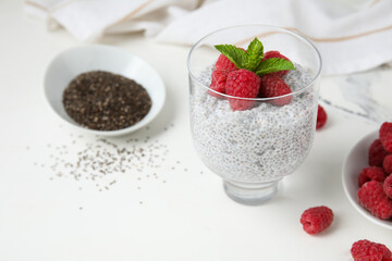 Glass of tasty chia seed pudding with fresh raspberries and mint on white background