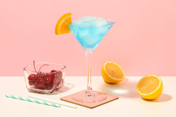 Glass of tasty Blue Lagoon cocktail garnished with orange and cherries on white table