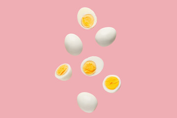 Flying boiled chicken eggs on pink background