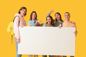 Group of students with blank poster on yellow background