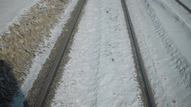 train rails streak past snowy ground as fast carriage moves along winter route, ground level view with parallel tracks, frost, long shadow, strong motion sense, cold travel mood in steady glide