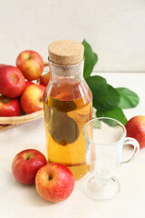 Bottle of fresh apple cider and wicker basket with fruits on white background