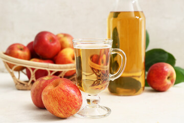 Glass cup and bottle of fresh apple cider with fruits on white background