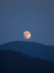 Moon rising above the horizon and hill