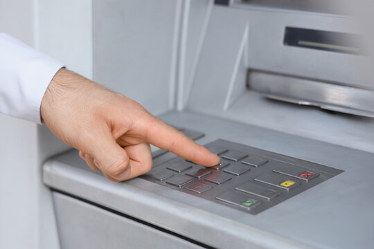 Male hand entering card's PIN code at ATM, closeup