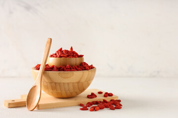 Wooden bowls with red dried goji berries on white background