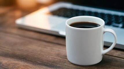 A steaming cup of coffee sits on a wooden table beside a laptop, evoking a cozy work atmosphere