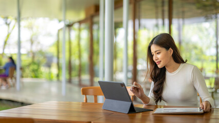 Businesswoman using tablet and stylus pen while working remotely in a modern cafe