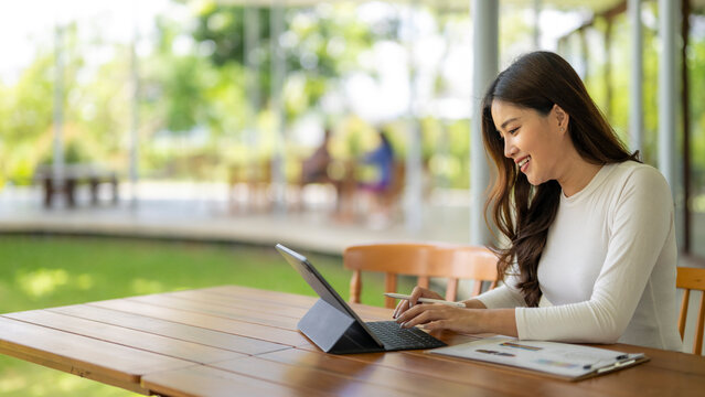 Young asian freelancer working on tablet in outdoor cafe
