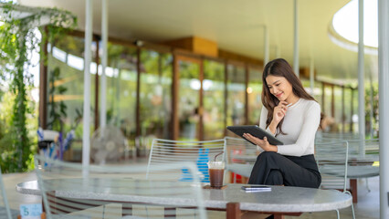 Businesswoman working remotely using digital tablet in outdoor cafe