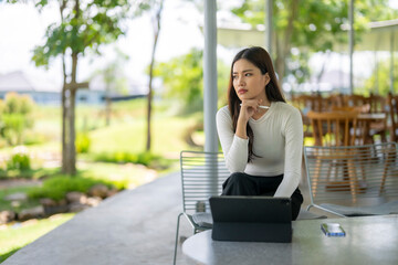 Fototapeta premium Businesswoman thinking and working with tablet in outdoor cafe