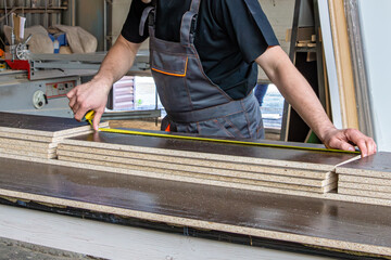 Carpenter Measuring Plywood Sheets with Selective Focus on the Tape Measure