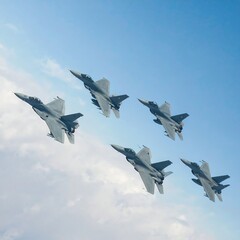 Fighter jets fly in formation against a blue sky